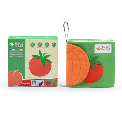 Montessori Fühlbuch Gemüse mit Verpackung. Das Buch hat Knisterpapier in Form eines Kürbis und bildet vorne eine Tomate ab. Außerdem hat es eine Schleife zum festmachen an z.B. Kinderwagen