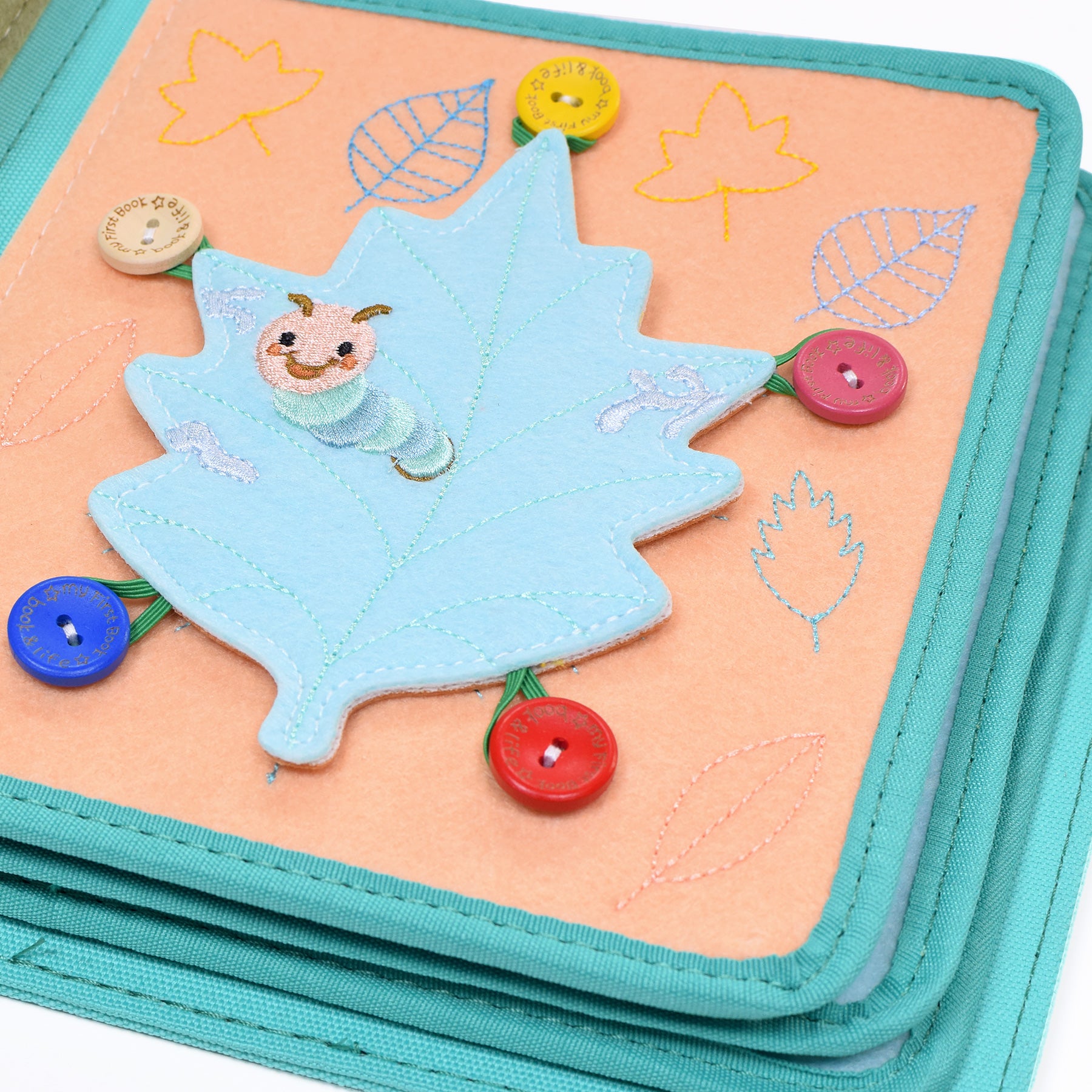 Ein Blatt mit einer Raupe befestigt mit Knöpfen an Gummis zum abmachen und anbringen als interaktive Übung